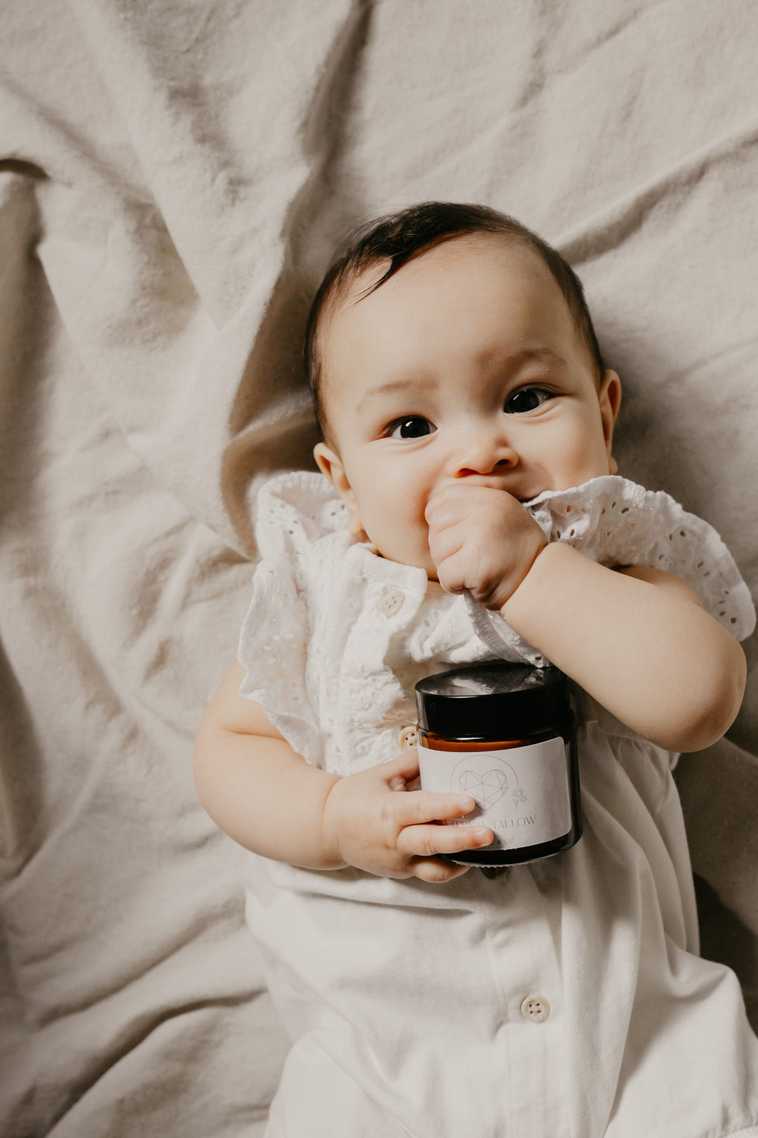 organic tallow balm by Eternal Tallow held by a baby in bed