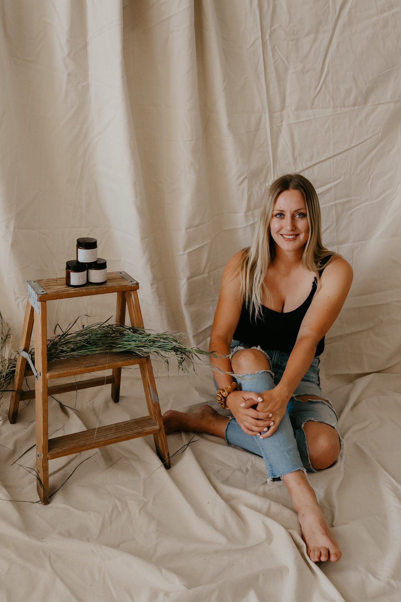 Eternal Tallow founder Kayla sits next to a bench with tallow skincare products