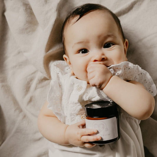 Baby holding Eternal Tallow's pure unscented tallow balm for face and body.