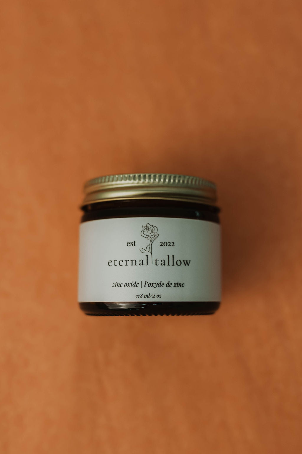 Jar of 'eternal tallow' zinc oxide lotion on a brown background